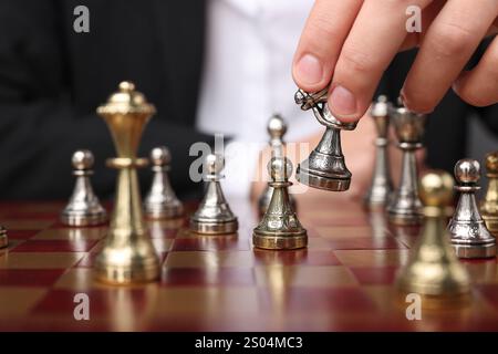 Uomo d'affari che gioca a scacchi sulla scacchiera, primo piano. Concetto di concorrenza Foto Stock