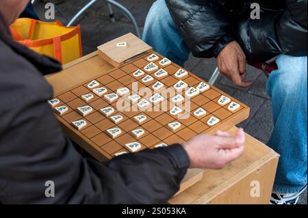 I concorrenti si sfidano a vicenda in un gioco da tavolo strategico chiamato shogi, o scacchi giapponesi, in un parco a Tennoji, Osaka, Giappone. Foto Stock