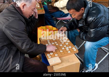 I concorrenti si sfidano a vicenda in un gioco da tavolo strategico chiamato shogi, o scacchi giapponesi, in un parco a Tennoji, Osaka, Giappone. Foto Stock
