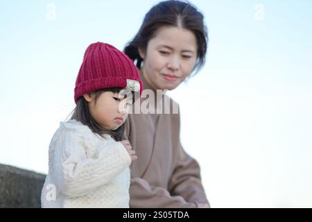 Una bambina di 5 mesi, una bambina di 3 anni e una donna giapponese di 30 anni trascorrono una fredda notte invernale seduta sui gradini di un parco sul mare ad Hakata, Foto Stock