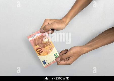 Mano umana che dà dieci banconote in euro in contanti su sfondo bianco. Finanza e moneta europea Foto Stock