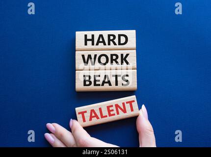Simbolo del talento. Parole concettuali il duro lavoro batte il talento sui blocchi di legno. Mano d'affari. Splendido sfondo blu intenso. Il lavoro e il duro lavoro battono le t Foto Stock
