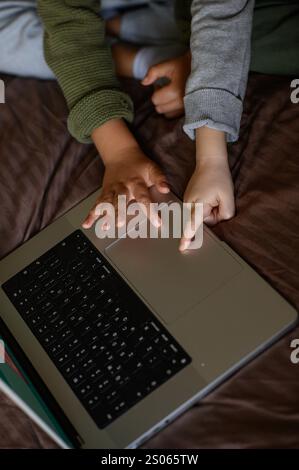 i bambini sono seduti davanti al portatile sul letto per un apprendimento adattivo Foto Stock