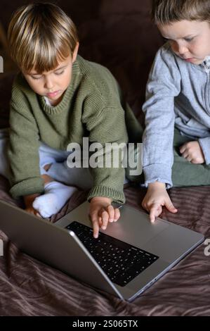 i bambini sono seduti davanti al portatile sul letto per un apprendimento adattivo Foto Stock