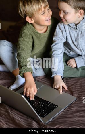 i bambini sono seduti davanti al portatile sul letto per un apprendimento adattivo Foto Stock