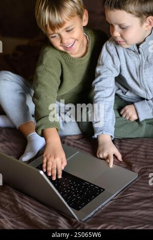 i bambini sono seduti davanti al portatile sul letto per un apprendimento adattivo Foto Stock