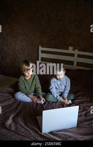 i bambini sono seduti davanti al portatile sul letto per un apprendimento adattivo Foto Stock