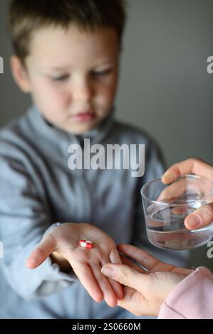 il ragazzo prenderà una pillola di supplemento Foto Stock