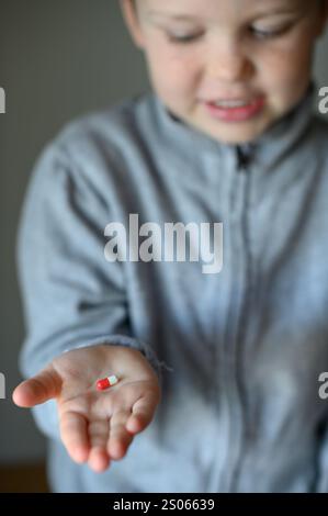 il ragazzo prenderà una pillola di supplemento Foto Stock