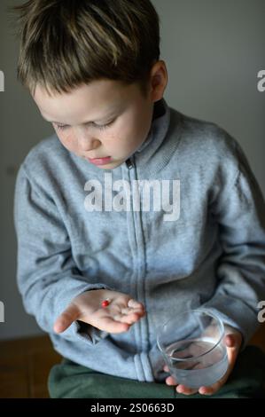 il ragazzo prenderà una pillola di supplemento Foto Stock