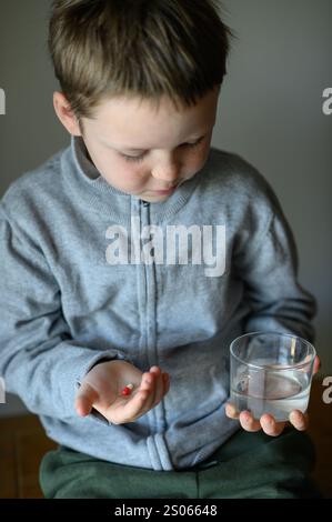 il ragazzo prenderà una pillola di supplemento Foto Stock