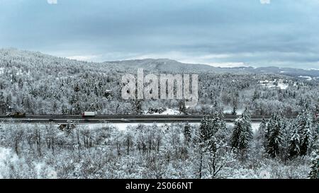 Vista aerea della Snowy Highway attraverso la Winter Forest Valley Foto Stock