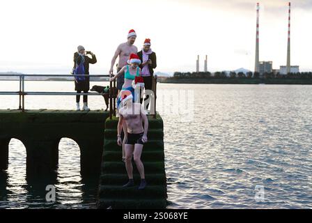 Le persone partecipano al Clontarf Yacht and Boat Club annuale di beneficenza Christmas Swim a Dublino in aiuto del RNLI. Data foto: Mercoledì 25 dicembre 2024. Foto Stock