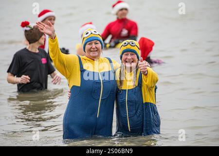 Boscombe, Bournemouth, Dorset, Regno Unito. 25 dicembre 2024. I festaioli del giorno di Natale che indossano un abito di lusso si recano al mare freddo per la nuotata di beneficenza White Christmas DIP, la più grande immersione natalizia del Regno Unito. L'evento raccoglie fondi per Macmillan che si prende cura localmente a Christchurch, un'unità di cura palliativa specialistica per i pazienti della comunità locale con malattie avanzate, progressiste o incurabili e per sostenere le loro famiglie. Ad oggi, questo evento ha raccolto oltre £ 330.000. Accreditamento John Rose/Alamy Live News Foto Stock