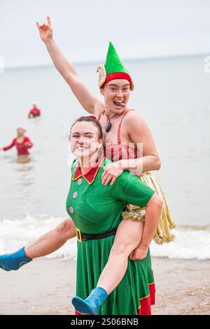 Boscombe, Bournemouth, Dorset, Regno Unito. 25 dicembre 2024. I festaioli del giorno di Natale che indossano un abito di lusso si recano al mare freddo per la nuotata di beneficenza White Christmas DIP, la più grande immersione natalizia del Regno Unito. L'evento raccoglie fondi per Macmillan che si prende cura localmente a Christchurch, un'unità di cura palliativa specialistica per i pazienti della comunità locale con malattie avanzate, progressiste o incurabili e per sostenere le loro famiglie. Ad oggi, questo evento ha raccolto oltre £ 330.000. Accreditamento John Rose/Alamy Live News Foto Stock