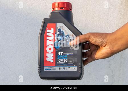 Una mano da donna mostra una bottiglia di olio motore a 4 tempi Motul 3000 4T Plus 10W-30 Premium Mineral. Kishoreganj, Bangladesh, 14 dicembre 2024. Foto Stock