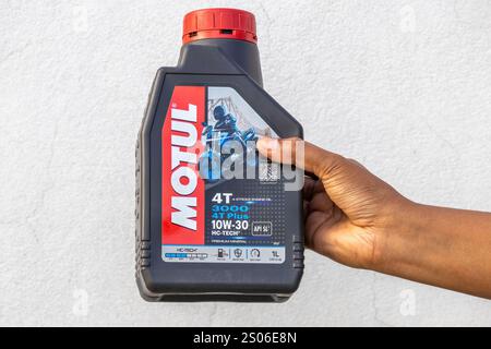 Una mano da donna che regge una bottiglia di olio motore a 4 tempi Motul 3000 4T Plus 10W-30 Premium Mineral. Kishoreganj, Bangladesh, 14 dicembre 2024. Foto Stock