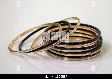 Eleganti bracciali in vetro nero e oro, visualizzati su uno sfondo piastrellato di legno. I Churis o braccialetti sono accessori di bellezza tradizionali indossati dalle donne asiatiche. Foto Stock