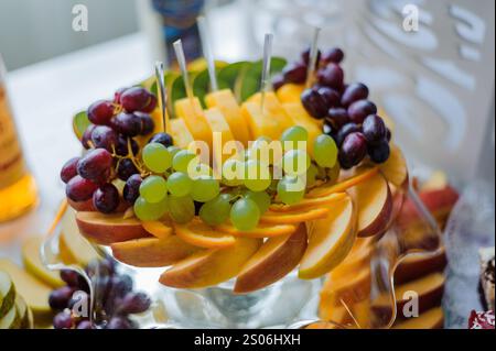 Vivace vassoio di frutta ripieno di frutta fresca assortita, tra cui uva e mele. Foto Stock