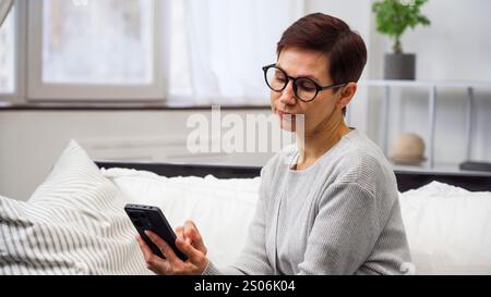 Una donna si siede sul divano e sfoglia i negozi online. Foto Stock