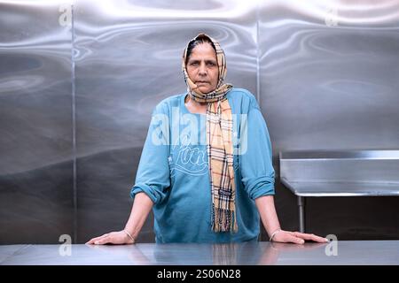 Foto in posa di un volontario langar che indossa un tradizionale telo chunni e una felpa con maniche arrotolate. In un tempio Sikh nel Queens, New Yo. Foto Stock