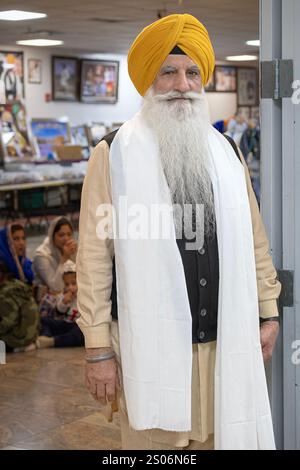 Un uomo Sikh più anziano che indossa un turbante dastare giallo e una lunga sciarpa bianca. In un tempio nel Queens, New York. Foto Stock