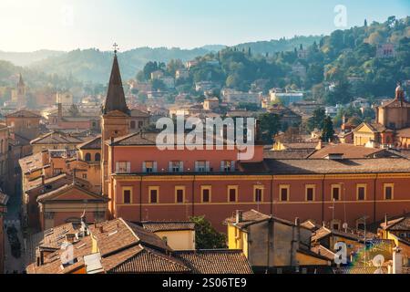 Vista aerea della città vecchia di Bologna, Emilia Romagna, Italia con tetti in tegole rosse, torre della chiesa, architettura medievale e verdi colline sullo sfondo a. Foto Stock