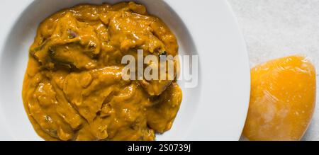 Vista dall'alto della zuppa nigeriana di owo con pesce e manzo in un piatto bianco, vista dall'alto della zuppa di oghwo in un ampio piatto da pranzo Foto Stock