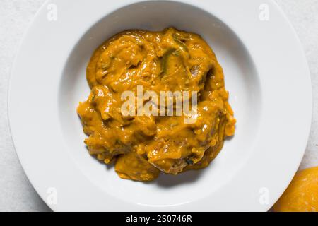 Vista dall'alto della zuppa nigeriana di owo con pesce e manzo in un piatto bianco, vista dall'alto della zuppa di oghwo in un ampio piatto da pranzo Foto Stock