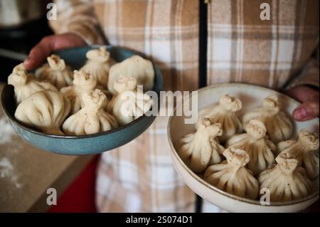 Due ciotole piene di gnocchi georgiani fatti in casa tenuti in mano all'interno. Foto Stock