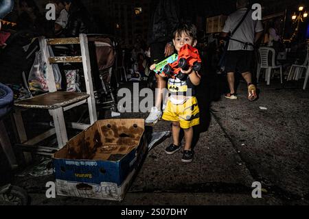 Buenos Aires, Argentina. 24 dicembre 2024. Un bambino regge il suo regalo di Natale. La cena della vigilia di Natale di fronte al Congresso Nazionale è stata organizzata dal gruppo Argentina Humana e dal movimento dei lavoratori esclusi (MTE) che è composto da centinaia di persone che si guadagnano da vivere riciclando rifiuti. Lo slogan era "Nessuna famiglia senza Natale”. Credito: SOPA Images Limited/Alamy Live News Foto Stock