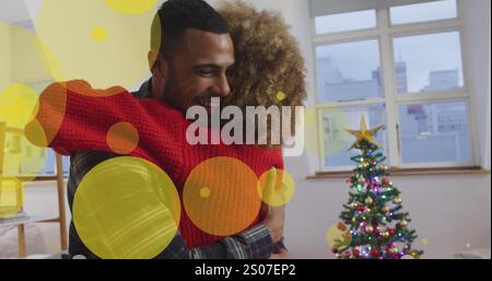 Immagine di puntini che si muovono sopra una coppia afroamericana che abbraccia sotto l'albero di natale Foto Stock