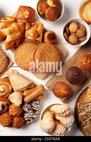 Prodotti da forno assortiti esposti su un tavolo di legno, con biscotti, pasticcini e muffin in un ambiente accogliente Foto Stock