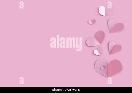 Molti cuori di coriandoli di carta su sfondo rosa. Modello banner per San Valentino Foto Stock