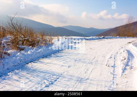 strada di campagna innevata. la vista era bellissima. tempo soleggiato. paesaggio di campagna tra i carpazi in inverno. nuvole nel cielo Foto Stock