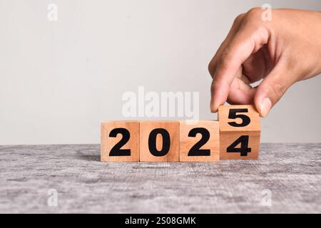 Capovolgere a mano blocchi di legno da 2024 a 2025, pianificazione aziendale e conto alla rovescia fino a 2025. Capovolgere l'anno dal 2024 al 2025 su cubetti di legno su un WO Foto Stock