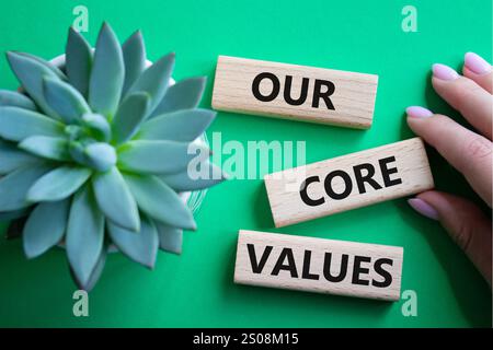 Simbolo dei nostri valori fondamentali. I nostri valori fondamentali sono parole concettuali sui blocchi di legno. Splendido sfondo verde con piante succulente. Mano d'affari. Business AN Foto Stock