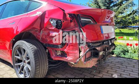 Vista ravvicinata dei danni alla vettura rossa dopo un incidente grave: Parti danneggiate, metallo deformato, elementi strappati Foto Stock