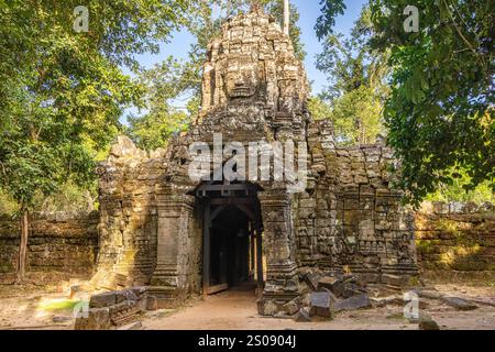 Antico tempio indù Ta Som khmer in rovina entance gopura porta con faccia in pietra sulla parte superiore e statue, parco archeologico di Angkor, Siem Reap, Cambogia Foto Stock