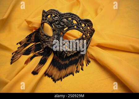 Maschera veneziana con perline adagiate su tessuto dorato attende la festa di carnevale. Foto Stock