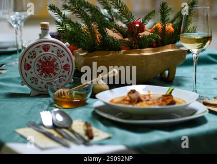 Tradizionale zuppa di cavolo natalizio con carne affumicata servita su un tavolo festivo con miele e vino bianco. Foto Stock