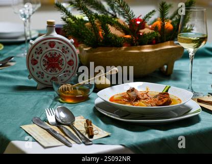 Tradizionale zuppa di cavolo natalizio con carne affumicata servita su un tavolo festivo con miele e vino bianco. Foto Stock