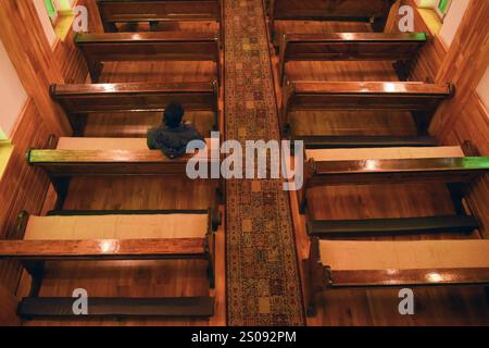 Un adoratore cristiano prega da solo all'interno della Chiesa cattolica della Sacra famiglia durante le celebrazioni natalizie a Srinagar, Jammu e Kashmir, il 25 dicembre 2024. Le ricerche del Regno Unito hanno rivelato che il numero di giovani che trascorrono il giorno di Natale da soli è aumentato di nove volte, confrontando le tendenze festive del 2024-1969. Lo studio condotto dal Policy Institute del King’s College di Londra ha dimostrato che il numero complessivo di persone che trascorrono il Natale da sole è più che raddoppiato, passando dal 5% all’11% negli ultimi 55 anni. Tra i 21 e i 34 anni, uno su 11 festeggerà la vacanza A. Foto Stock