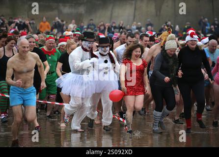 26 dicembre 2024, Cromer, Inghilterra, Regno Unito: Partecipanti a vari abiti di fantasia sprint verso il mare all'inizio del Cromer DIP. I North Norfolk Beach Runners organizzano l'evento annuale che è diventato parte della tradizione del Santo Stefano a Cromer. Il tuffo dove centinaia di persone, alcune in abiti eleganti, corrono nel Mare del Nord è iniziato nel 1985. (Credit Image: © Martin Pope/ZUMA Press Wire) SOLO PER USO EDITORIALE! Non per USO commerciale! Foto Stock