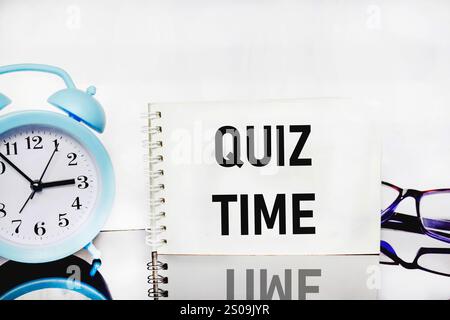 L'ora del Quiz sull'iscrizione accanto alla sveglia su sfondo bianco. il concetto di rispondere a domande o giochi a quiz. spazio di testo Foto Stock