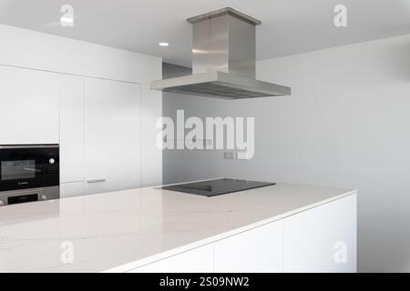Cucina bianca moderna e minimalista con isola, piano cottura e cappa Foto Stock