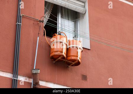 Vecchia casa spagnola con due bombole di gas butano arancioni appese fuori da una finestra, fornendo energia per il riscaldamento e la cottura Foto Stock