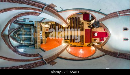 L'immagine cattura una vista aerea dell'interno di una cattedrale, caratterizzata da intricati archi in mattoni, pali di legno, un altare con moquette rossa e un prominente Foto Stock