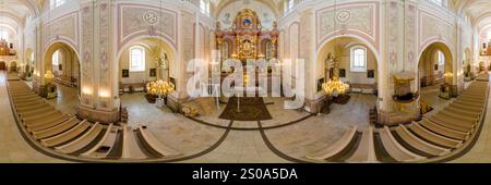 Vista panoramica dell'interno della cattedrale di Aglona, Lettonia, con un altare decorato, soffitto a volta, affreschi e lampadari su una spaziosa navata Foto Stock