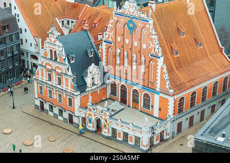 L'immagine cattura la Casa delle teste nere con la sua facciata gotica ornata, mattoni rossi e accenti bianchi, circondata da strade acciottolate a riga. Foto Stock